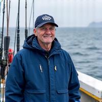 Professional fishing guide smiling on his boat with fishing rods.