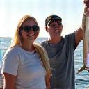 A smiling family on a fishing boat, holding up a medium-sized fish.